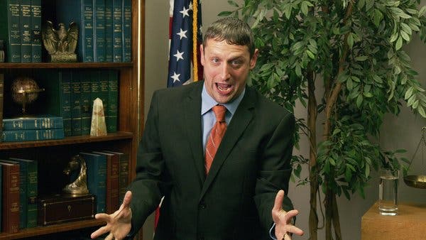 A man in a suit in a lawyerâs office yells at the camera