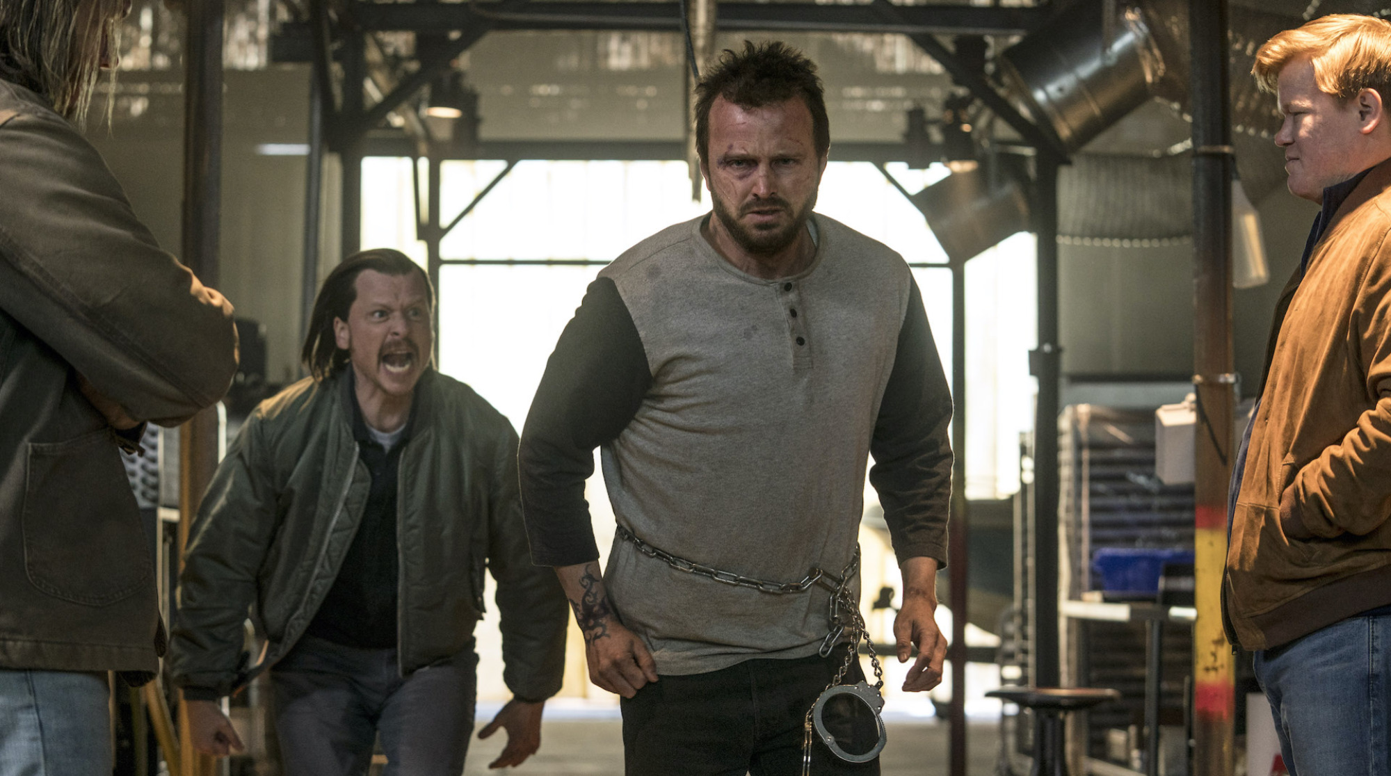 A man with close-cropped hair running through a factory.
