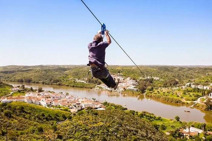 A person ziplines across the border of Spain and Portugal