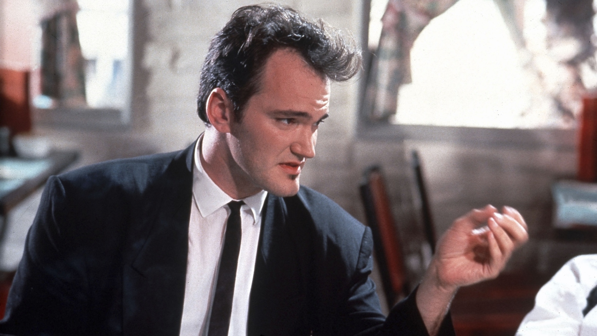 An individual dressed formally holds a cigarette.