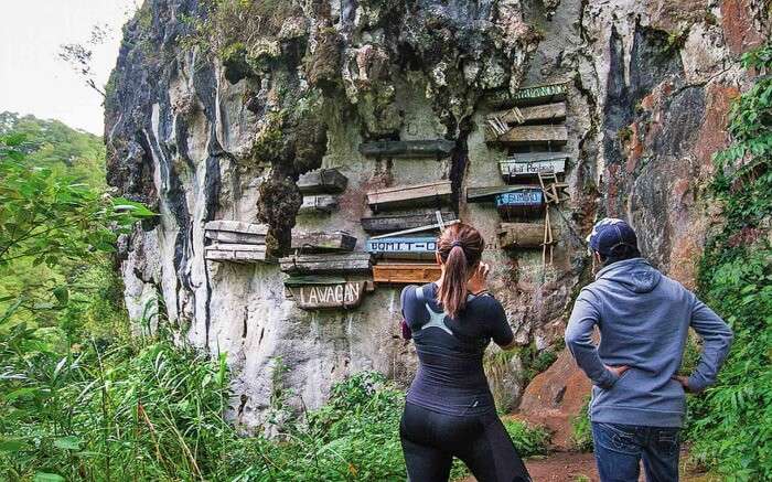 Couple looking at hanging coffins in Sagada Mountain Province in Philippines