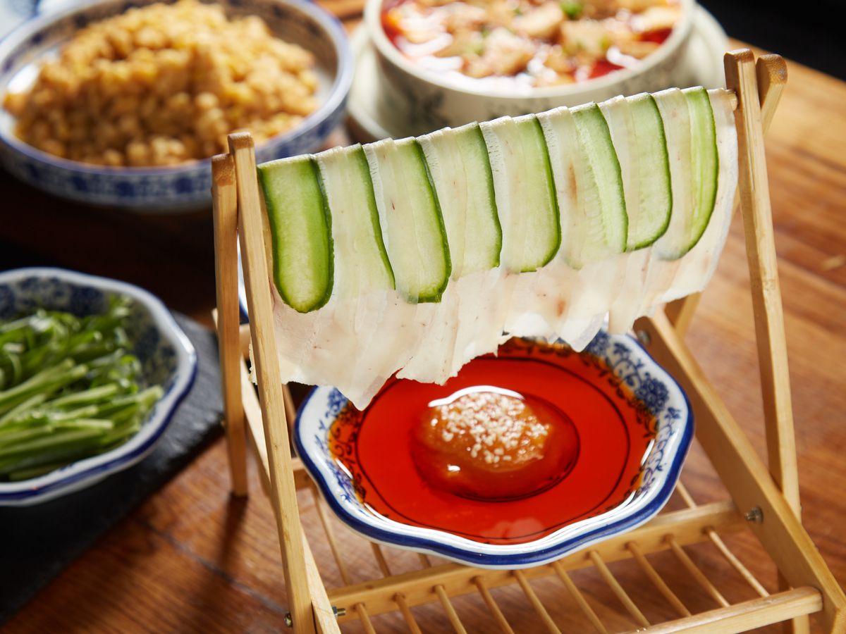 Sliced pork belly and cucumber arranged to resemble drying laundry, served with chile garlic sauce underneath