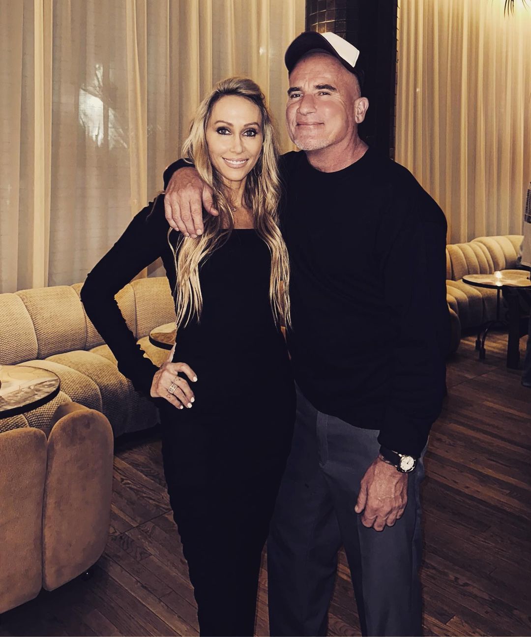 Tish Cyrus and Dominic Purcell wearing black smiling for the camera