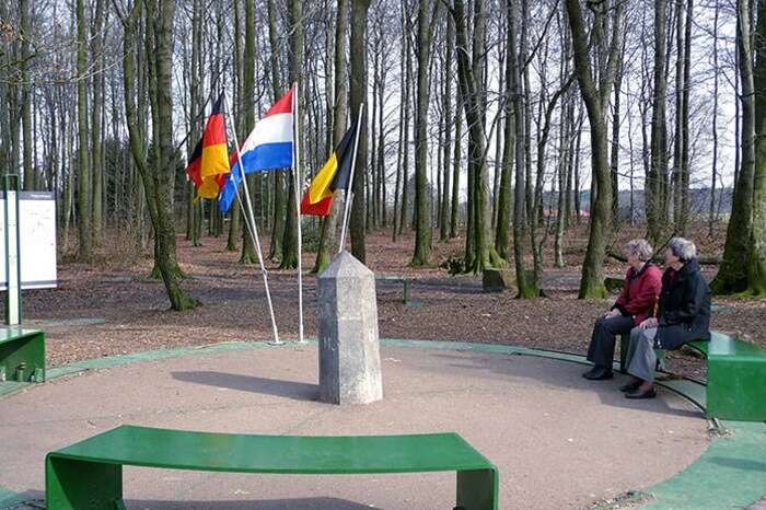 Tourists sit at the round seating arrangement at the border of Germany-Netherlands-Belgium