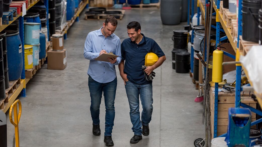 men walking in a warehouse looking at a document